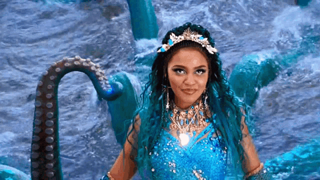 a woman with blue hair and a tiara is standing in the water with an octopus .