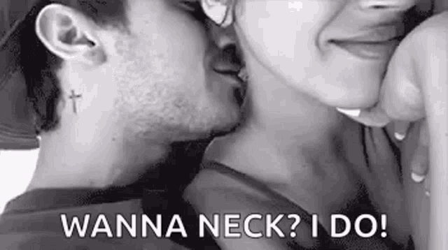 a black and white photo of a man kissing a woman 's neck .