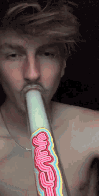 a shirtless man is smoking a bong with a sticker on it that says ' sling '