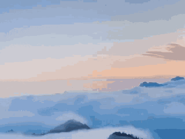 a view of a mountain range covered in fog at sunset