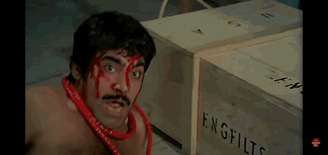 a shirtless man is tied to a box with a red rope around his neck .