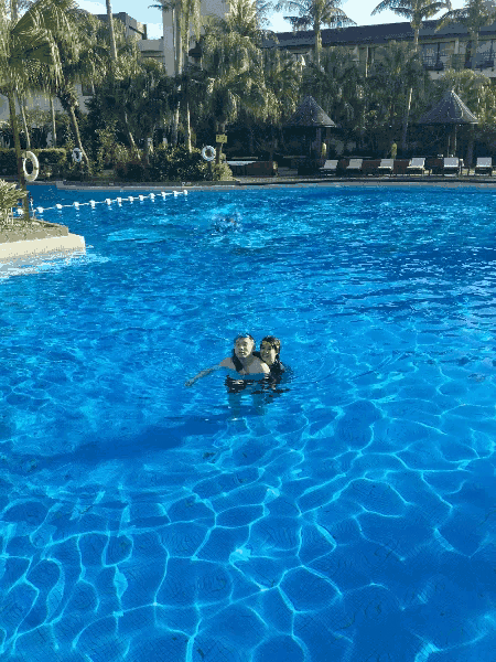 a couple of people are swimming in a large pool