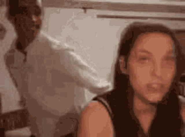 a man is standing behind a woman in a kitchen and looking at her .