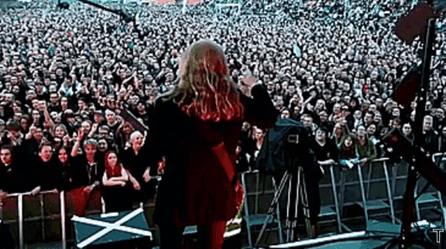 a woman stands in front of a crowd at a concert