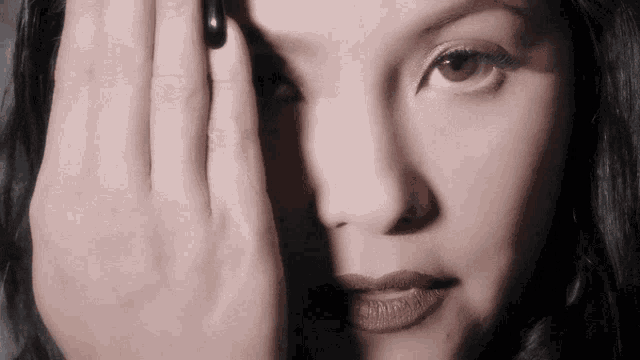 a close up of a woman 's face with her hand on her eye