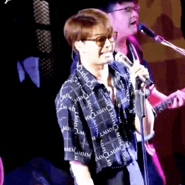 a man singing into a microphone while wearing a shirt that says mm on it