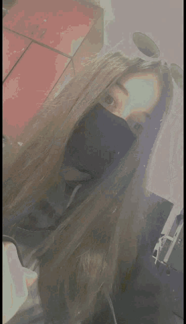 a woman 's hair is being blow dried by a person wearing a black hoodie