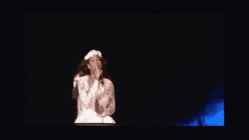 a woman is singing into a microphone on a stage in front of a crowd
