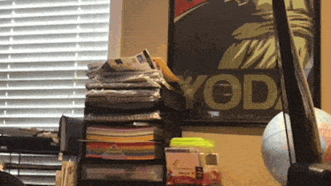a stack of books sits on a desk in front of a yod poster