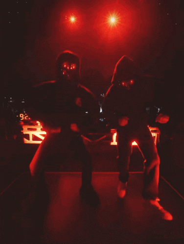 two men wearing masks and hoodies are dancing on stage
