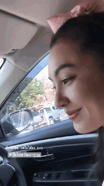 a woman is sitting in a car with a sticker that says ' bangkok ' on it