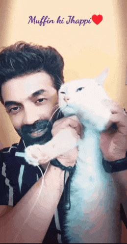 a man with a beard is holding a white cat with the words muffin ki jhappi written above him