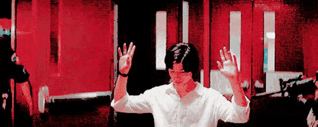 a man in a white shirt is waving his hands in front of a red door