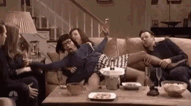 a group of people are sitting on a couch with a woman laying on a man 's lap .