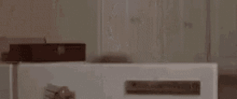 a woman with a white mask on her face is standing in front of a refrigerator with the words `` hello '' written on it .