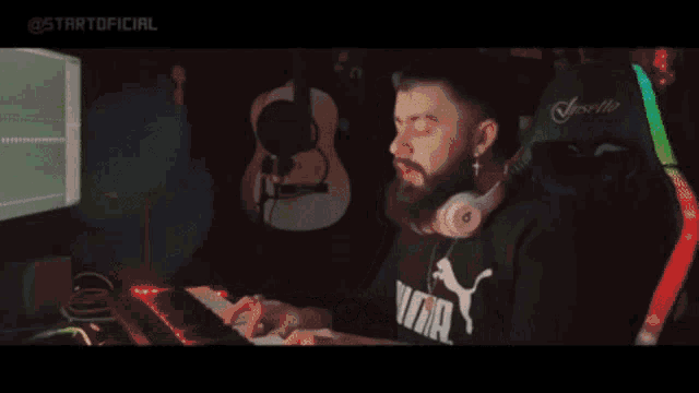 a man with a beard is sitting in front of a computer with the word enqui written on the screen .