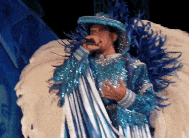 a man in a blue and white feathered outfit is singing into a microphone