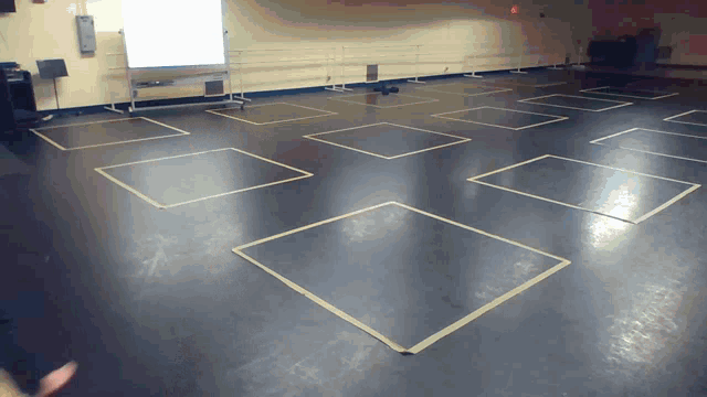 a dance studio with squares on the floor and yellow lines