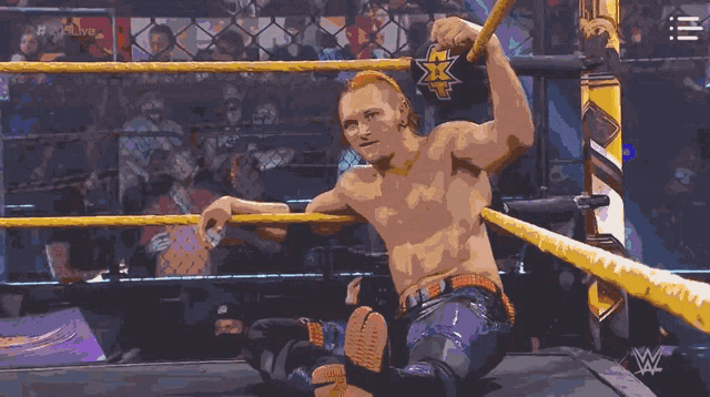 a shirtless wrestler in a wrestling ring with the letters w on the wall behind him