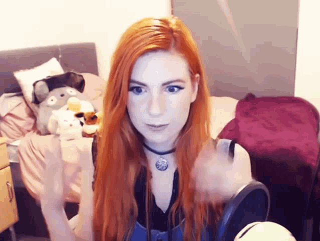 a woman with red hair is standing in front of a microphone in a bedroom