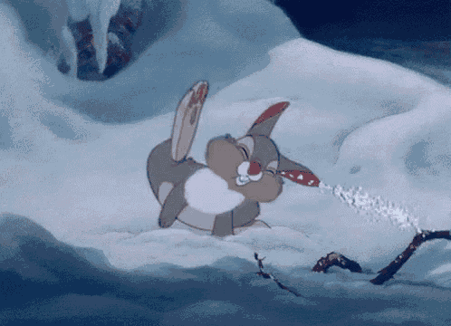 a cartoon rabbit is laying in the snow and blowing snow out of its mouth