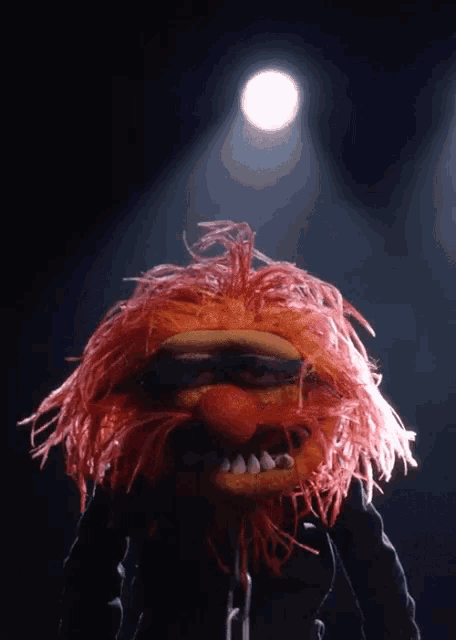a muppet with red hair is standing in front of a light
