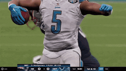 a football player with the number 5 on his jersey is holding a ball