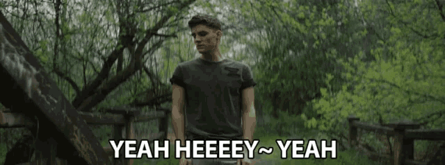 a man is standing in a forest with the words yeah heeeey yeah behind him