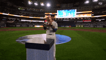 a baseball player holds a trophy in a stadium that says sn on the bottom