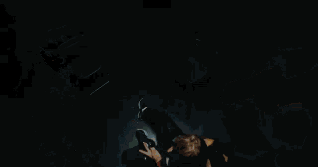 a man in a blue shirt is dancing in a dark room with a blurred image of his face .