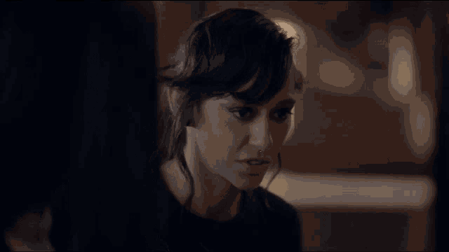 a woman with a nose ring is talking to another woman in a dark room .