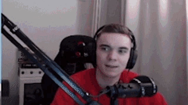 a young man wearing headphones is sitting in front of a microphone in a room .