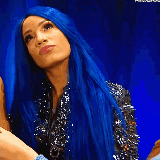 a woman with blue hair is wearing a jacket with spikes