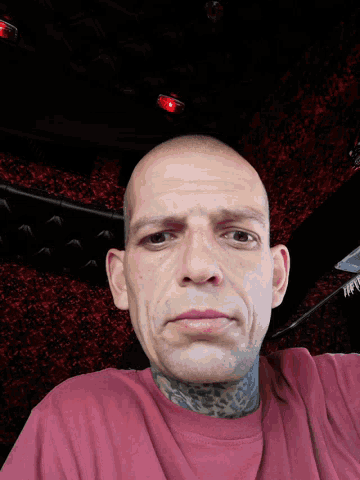 a man with a tattoo on his neck is wearing a pink sweater