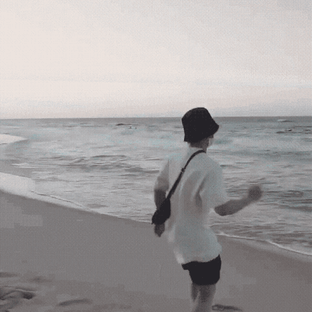 a man in a white shirt and black shorts is running on the beach