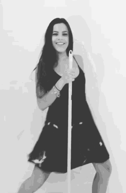 a woman in a black dress is holding a mop