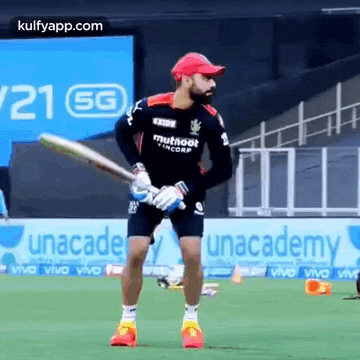 a cricket player is holding a bat in his hands on a field .