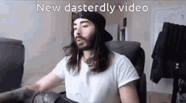 a man with long hair and a beard is sitting in a chair in front of a computer screen .