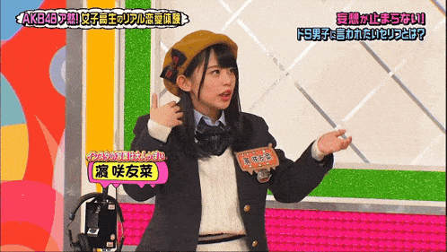 a girl in a school uniform stands in front of a colorful wall with chinese writing on it