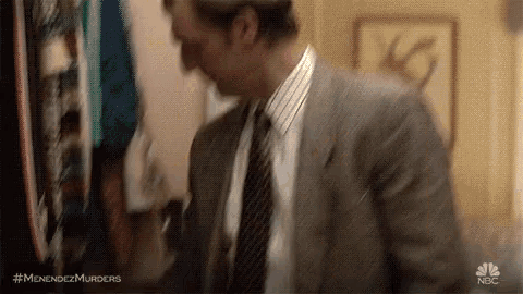 a man in a suit and tie is standing in front of a painting .