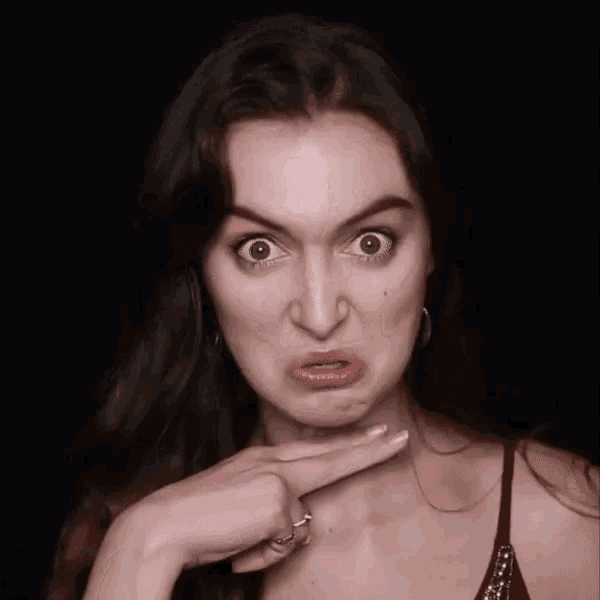 a woman is making a funny face with her finger to her face .