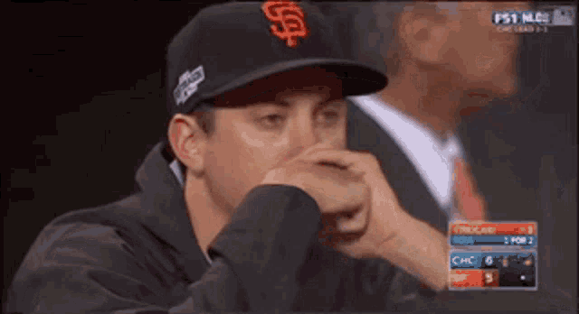 a man wearing a giants hat covering his nose