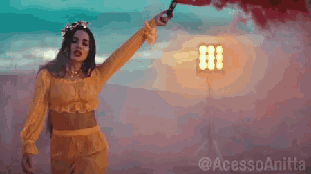 a woman in a yellow top is holding a red smoke bomb .