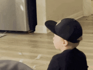 a young boy wearing a black hat is sitting on the floor looking at something .