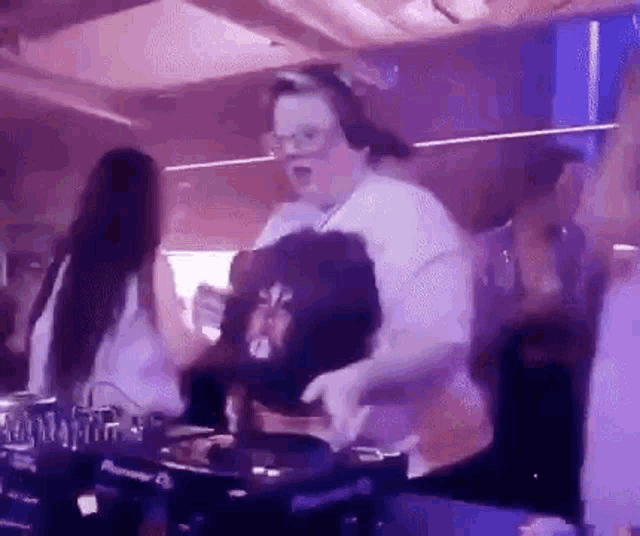 a man is dancing in a club while playing music on a dj .