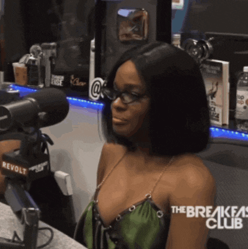a woman wearing glasses is sitting in front of a microphone with the breakfast club written on it