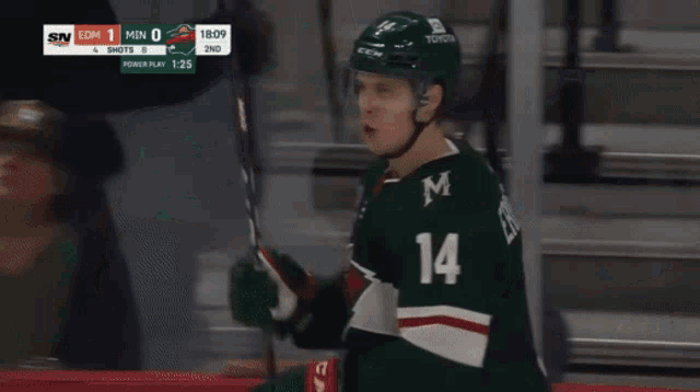 a hockey player with the number 14 on his jersey is holding a hockey stick