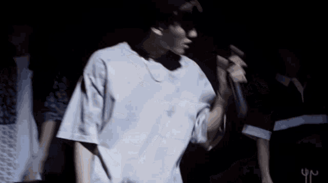 a man in a white shirt is holding a microphone in a dark room .