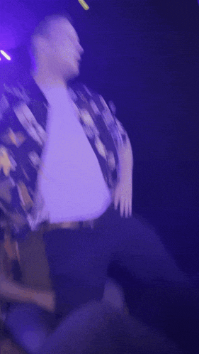 a man in a hawaiian shirt dancing in a dark room