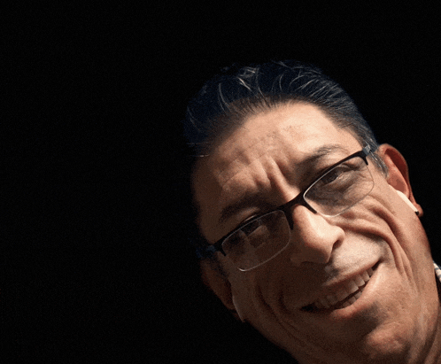 a man wearing glasses is smiling with his mouth open